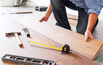 Contractor installing planks of hardwood flooring