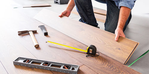 Professional installer installing hardwood flooring planks
